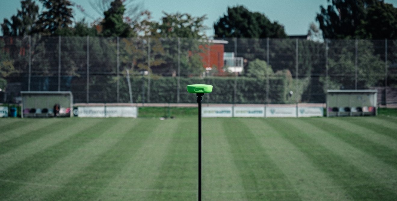 A green camera at the half way line on a sports pitch