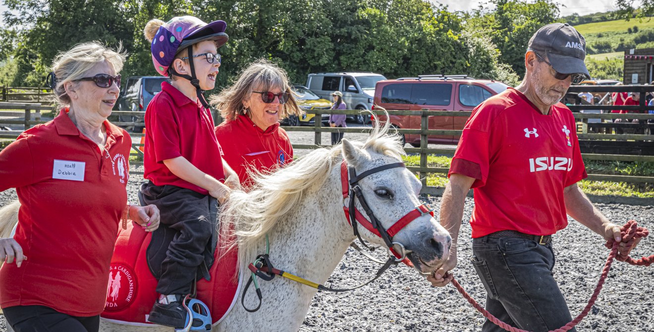 Iori on a horse, supported by volunteers