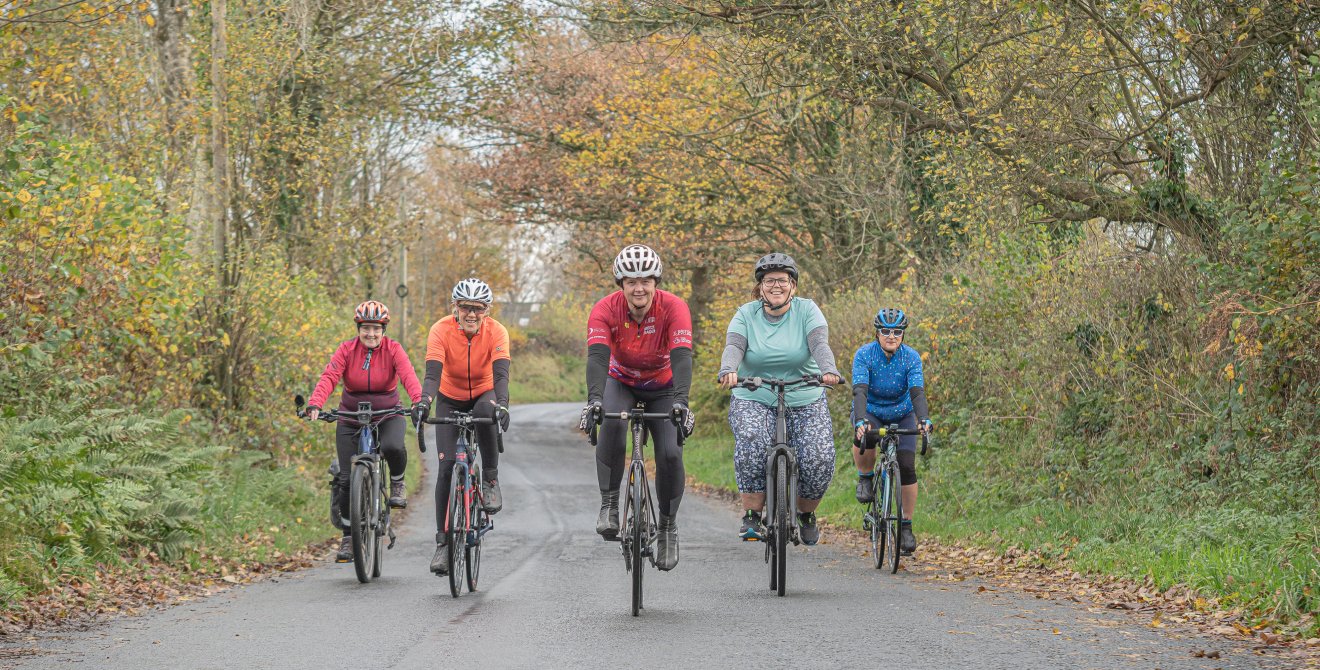 five members of Breeze cycling riding on a tree lined path