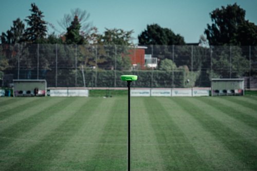 A green camera at the half way line on a sports pitch