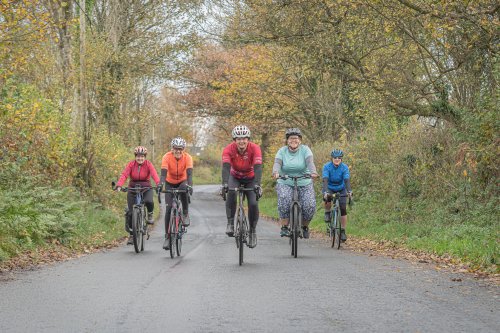 five members of Breeze cycling riding on a tree lined path