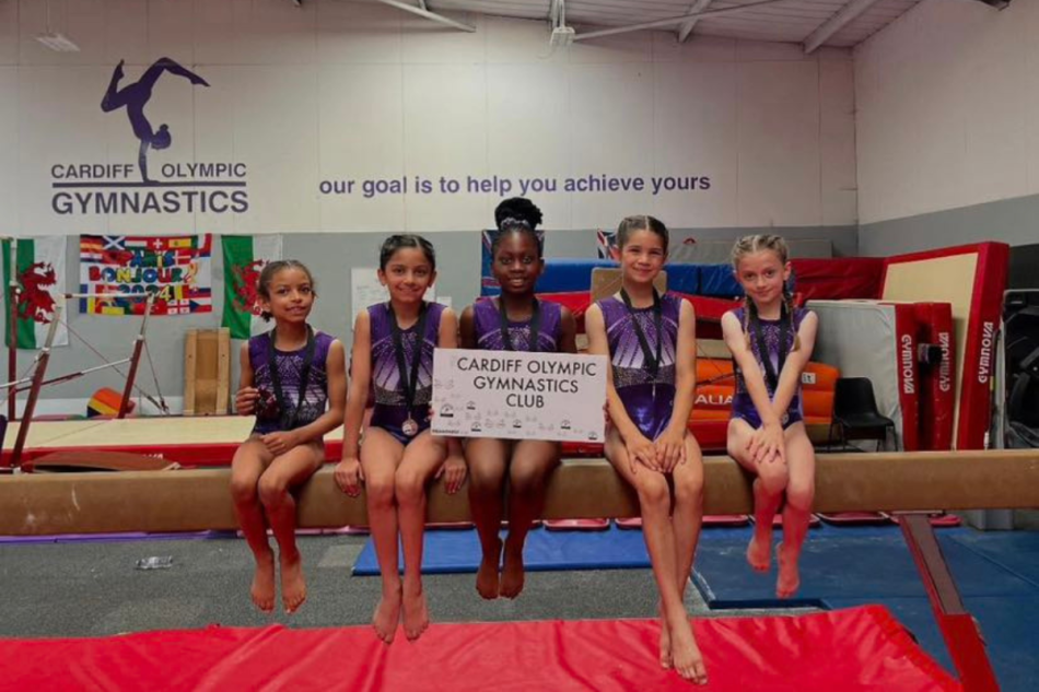 Five young girls sat on a balance beam