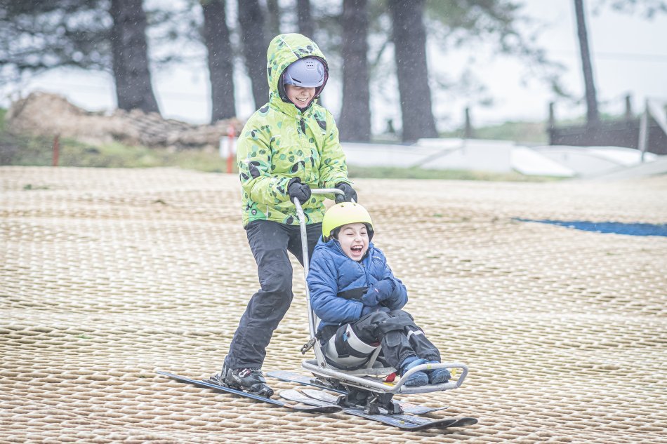 A member of the team pushes a participant on a sit ski