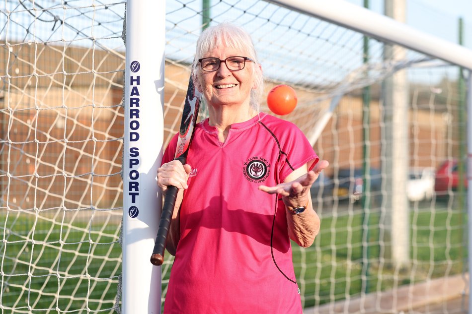 Mair holding a hockey stick and catching ball.